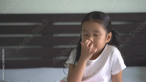 Asian child cute or kid girl enjoy nose picking or picky by finger with snot on bed and preschool or 5 years old with wear white t-shirt on 4K