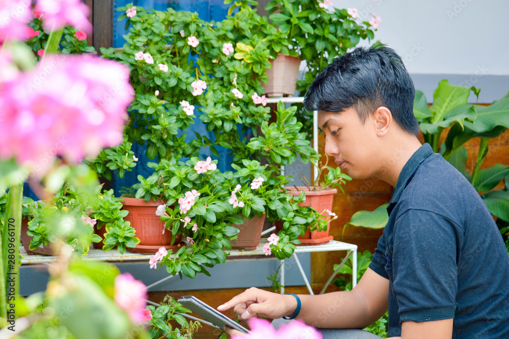 young asian male worker doing research at garden farm using tablet pc. modern garden concept