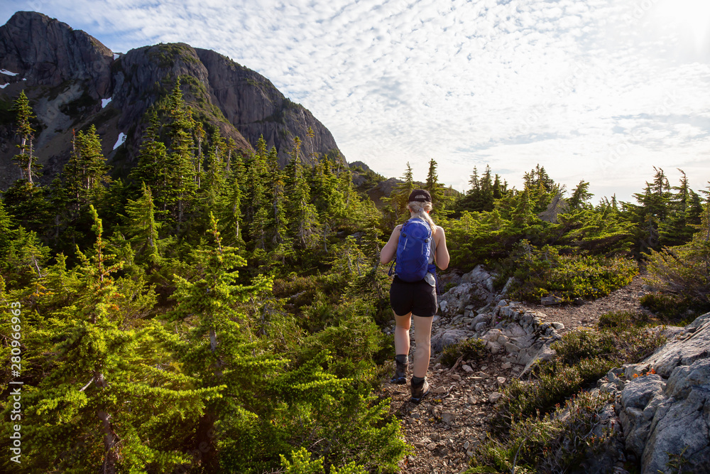 Adventurous girl hiking the beautiful trail in the Canadian Mountain Landscape during a vibrant summer evening. Taken at Mt Arrowsmith, near Nanaimo, Vancouver Island, BC, Canada. Adventurous girl hiking the beautiful trail in the Canadian Mountain Landscape during a vibrant summer evening. Taken at Mt Arrowsmith, near Nanaimo, Vancouver Island, BC, Canada.