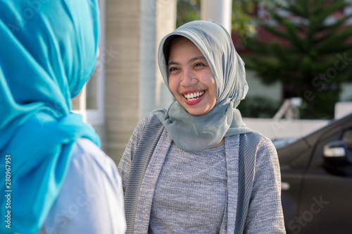 portrait of two neighboring hijab women were having a conversation in front of the house
