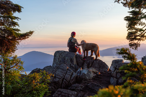 Canvas Print Adventurous Girl is hiking with a dog on top of St