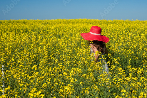 Young girl inred straw hat in a canola or rapeseed field in Saskatchewan Canada photo