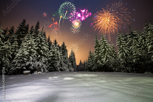 Winter night landscape with forest, pink polar light and fireworks over the taiga. New Year card with forest, fireworks and pink sky.