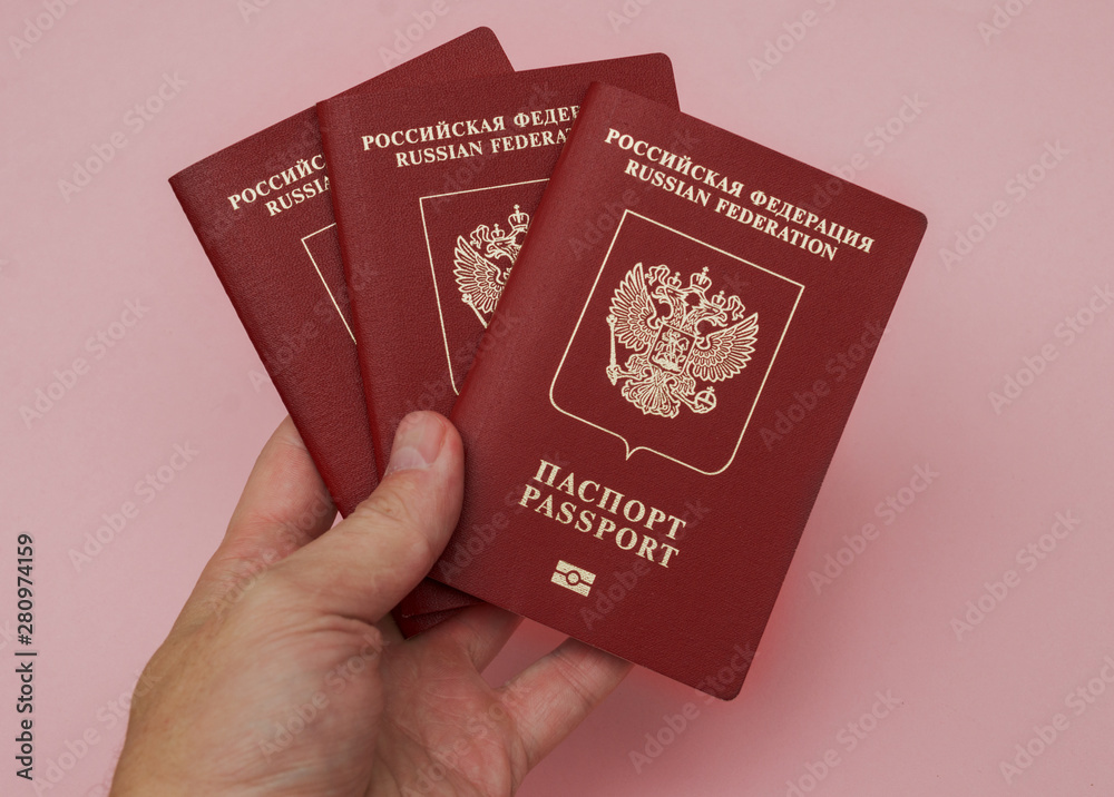 Russian international passport in a man's hand on a pink background Russian international passport in a man's hand on a pink background