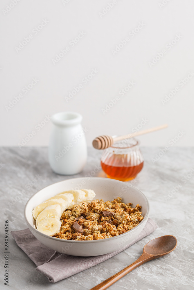 Breakfast with granola with banana. Jar of honey on background Breakfast with granola with banana. Jar of honey on background