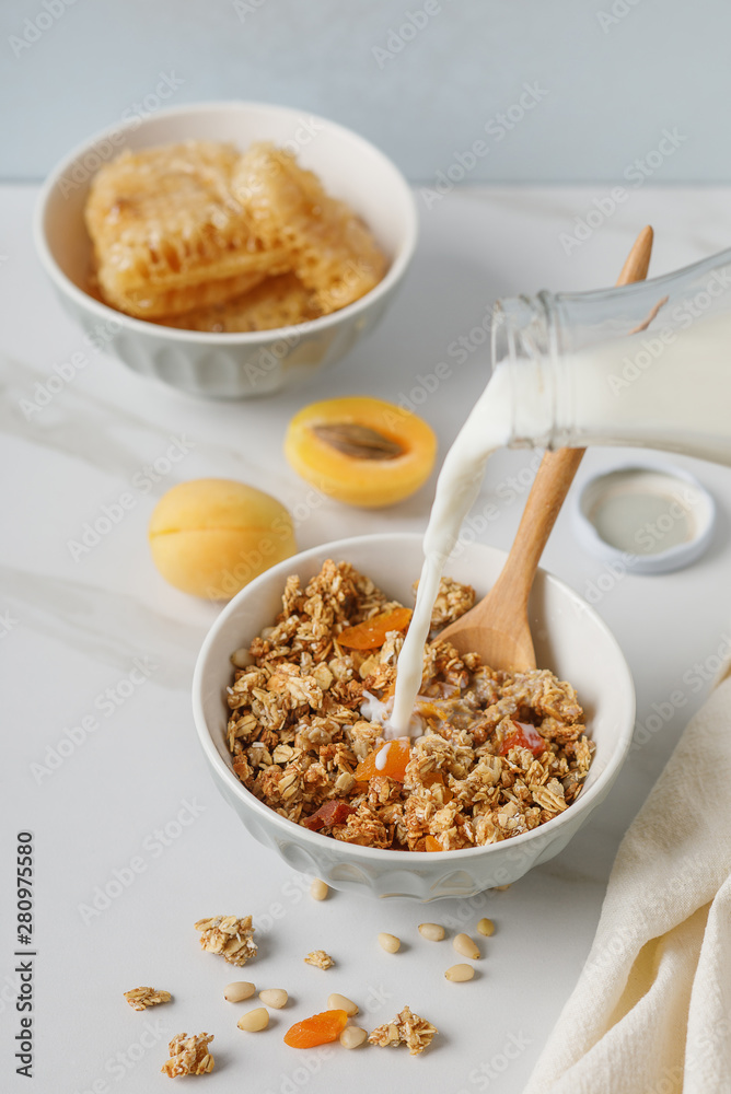 Bowl of granola with dried apricot on white table. Wooden spoon. Bowl of granola with dried apricot on white table. Wooden spoon.