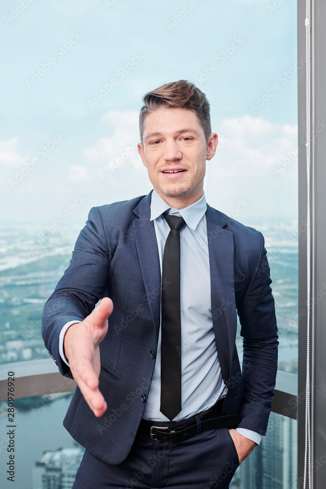 Attractive young businessman offering hand for handshake whne meeting with client or colleague Attractive young businessman offering hand for handshake whne meeting with client or colleague