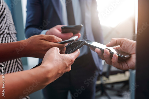 Close-up image of business people sharing media files via smartphone applications