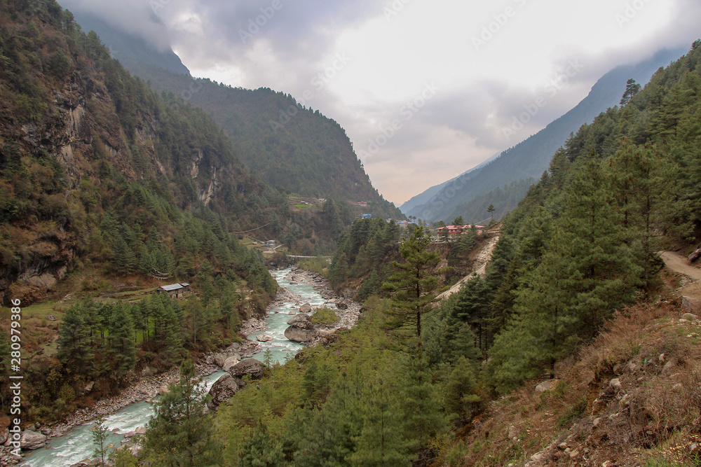 Dudh Koshi snow river (Dudh Kosi river or Milk-Koshi River) flows in mountain valley near Phakding village in Himalayas in Nepal. Nature, Lakes and Rivers, Mountains, Travel and Tourism concept. - obrazy, fototapety, plakaty 