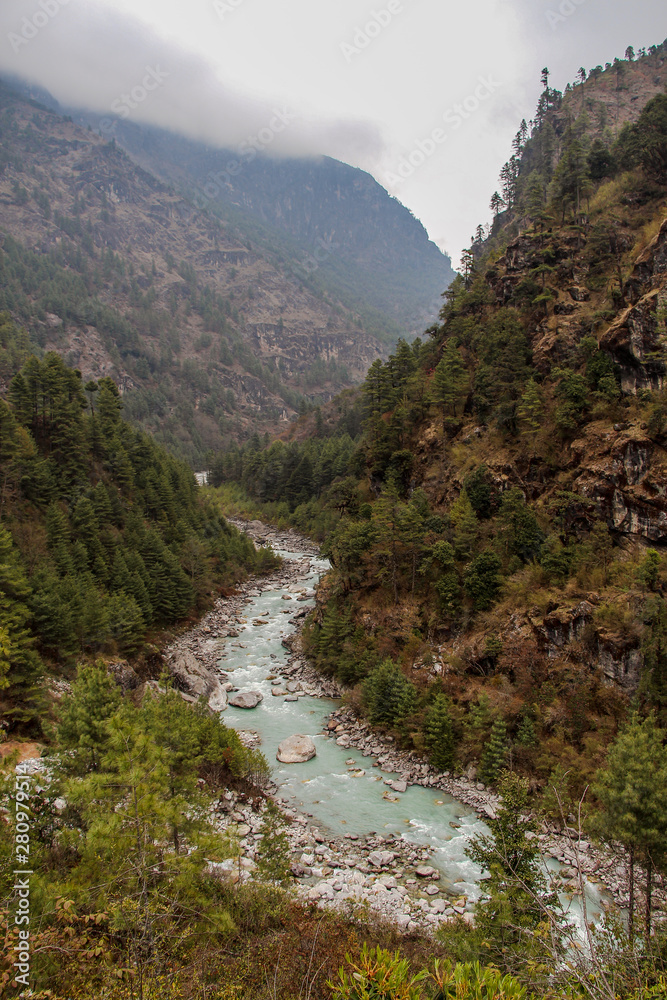 Dudh Koshi snow river (or Dudh Kosi river) flows in mountain valley near Phakding village in Himalayas in Nepal. Nature, Lakes and Rivers, Mountains, Travel and Tourism concept. - obrazy, fototapety, plakaty 