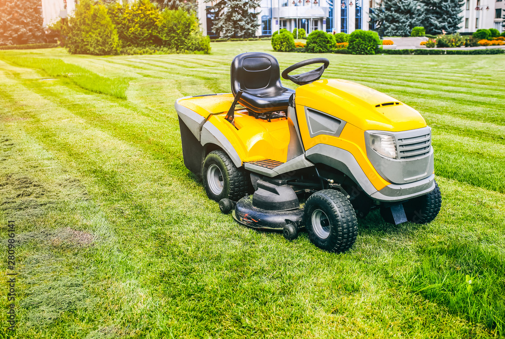 Grass cutter in the work.  Machine for cutting lawn is standing outdoors. Summer bright photo.