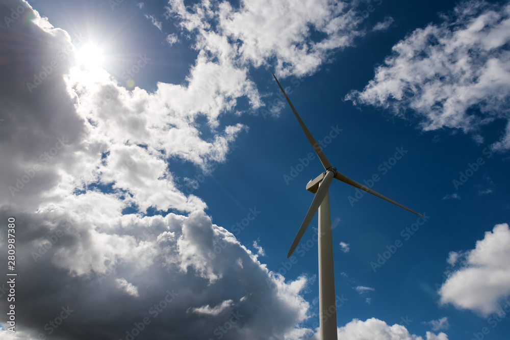 Sun shinig on wind turbine, cloudy blue sky backround Sun shinig on wind turbine, cloudy blue sky backround