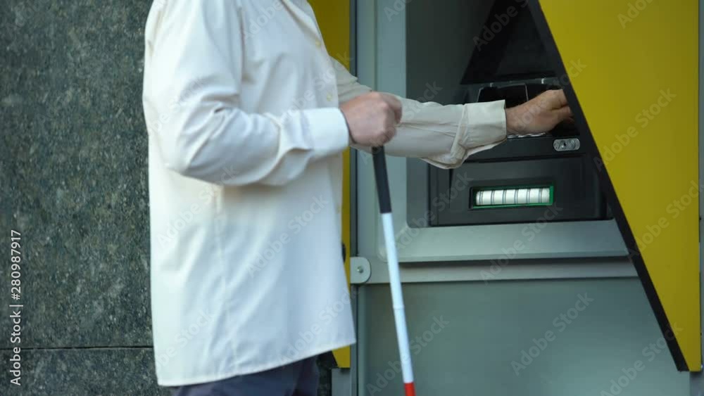Blind man withdrawing money from atm, searching tactile indicator to insert card Blind man withdrawing money from atm, searching tactile indicator to insert card