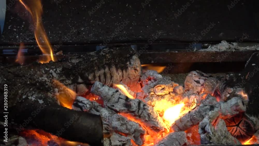 Bright fire flame from burning firewood from fruit trees on an open grill in the evening Bright fire flame from burning firewood from fruit trees on an open grill in the evening