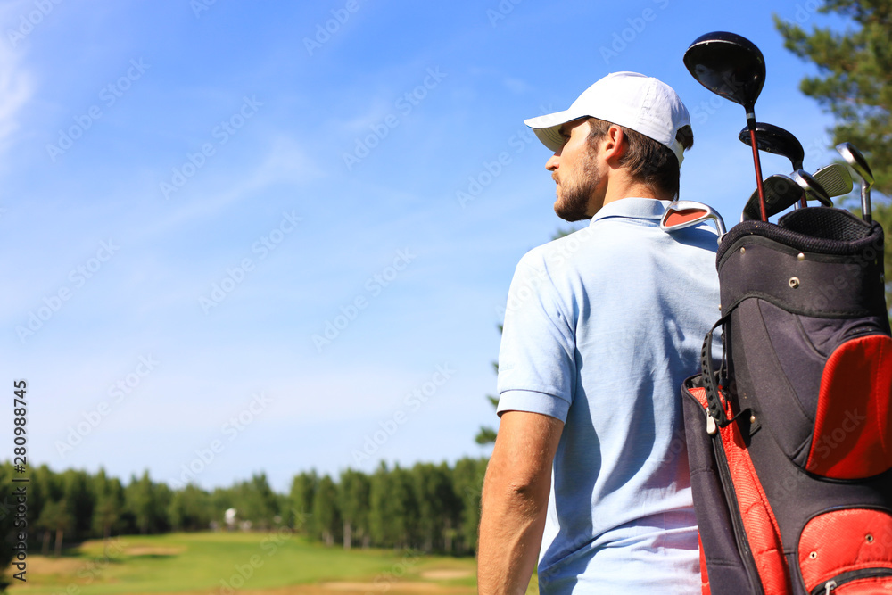 Golf player walking and carrying bag on course during summer game golfing.
