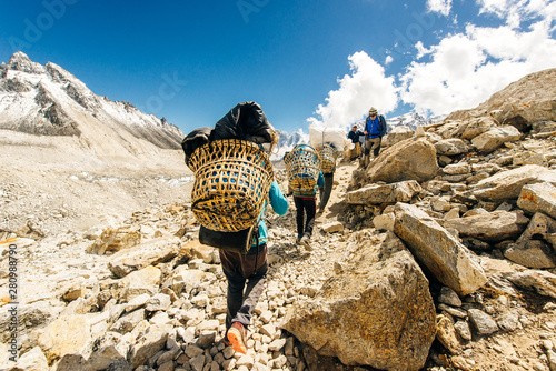Porter and Sherpa walking with big bag baggage luggage in Himalaya Mountains in Nepal.