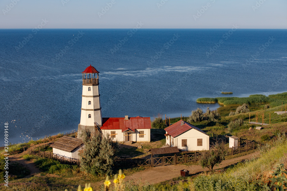Old lighthouse with a red roof on the sea shore in the morning