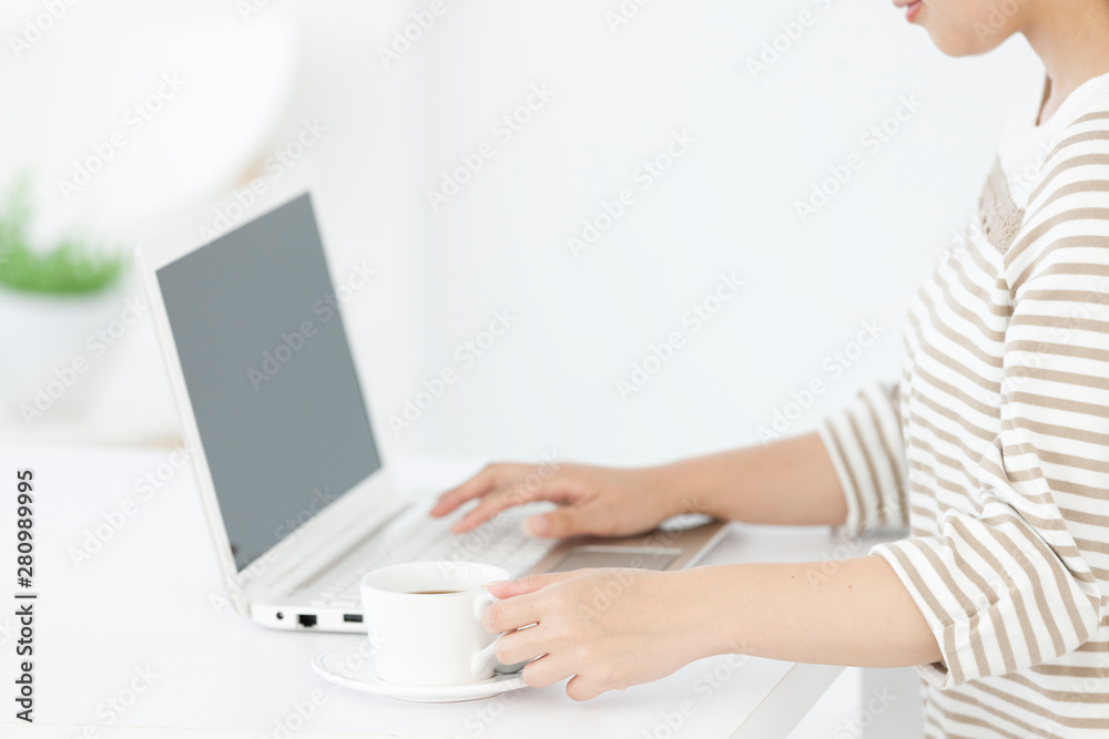 コーヒーを飲みながらパソコンを操作する女性