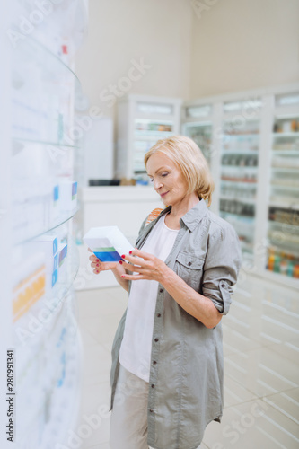 Positive delighted woman looking at package with pills