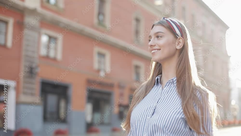 Cute woman wearing in blue and white striped dress shirt walking on the street look at camera spinning happy smile beautiful portrait fashion face female. Cute woman wearing in blue and white striped dress shirt walking on the street look at camera spinning happy smile beautiful portrait fashion face female.
