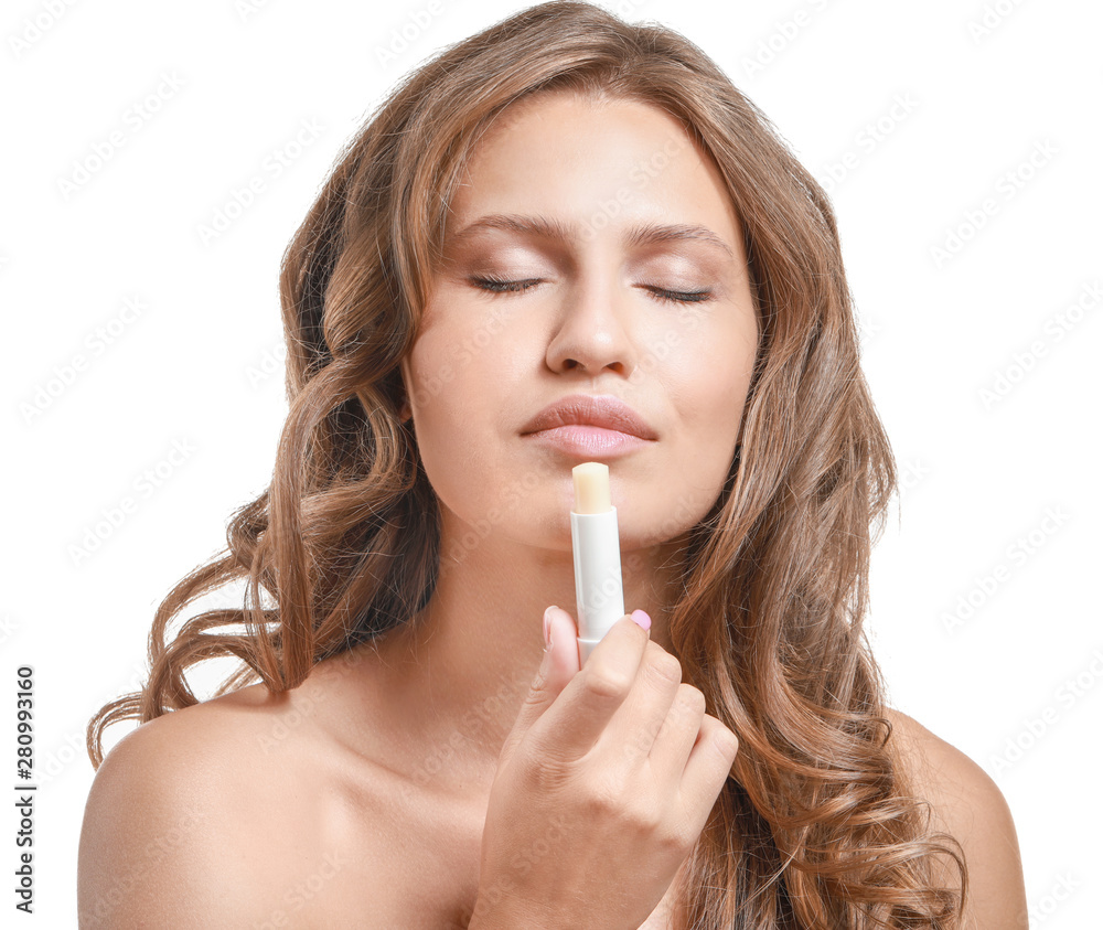 Beautiful young woman applying lipstick against white background Beautiful young woman applying lipstick against white background