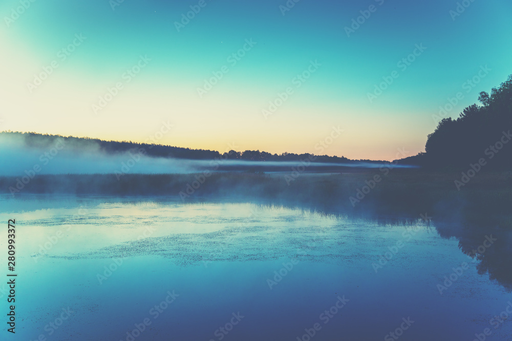 Fototapeta premium The magical foggy sunrise over the lake. Rural landscape. Summer landscape in the early morning
