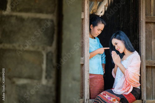 Mother and two daughters in an ancient Thai dress are scolding the daughter from the wooden window. © subinpumsom