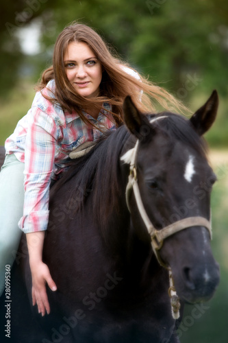 young woman sitting on her black horse © wernerimages