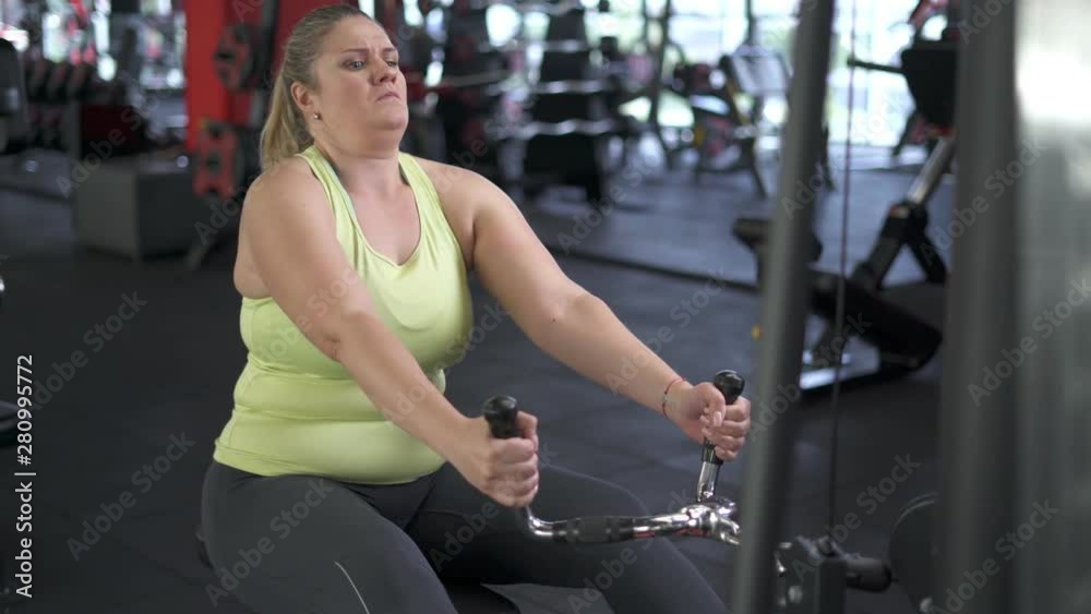 Plus Size Model, woman trains in Gym, lifting blocks on rack machine, training muscles on block device and gym equipment. Plus Size Model, woman trains in Gym, lifting blocks on rack machine, training muscles on block device and gym equipment.