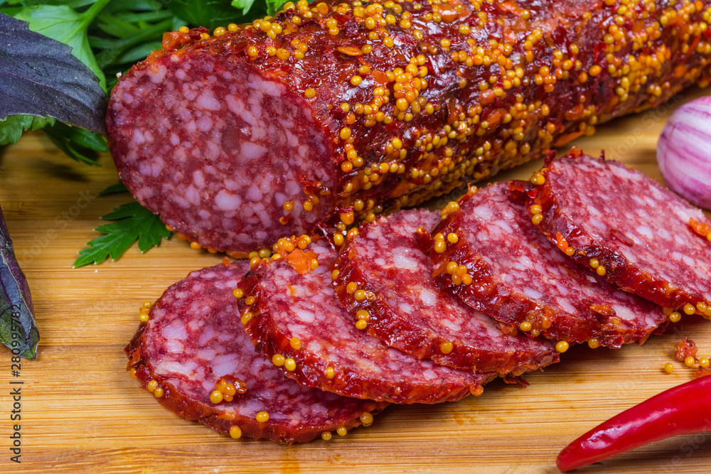 Partly sliced salami covered with French mustard close-up Partly sliced salami covered with French mustard close-up