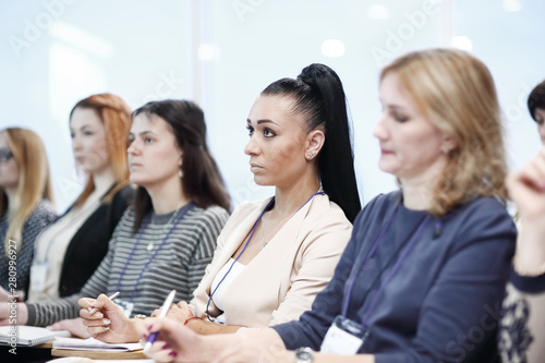 listeners take notes in notebooks,sitting in the conference room