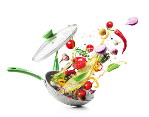 Cooking concept. Vegetables are flying out of the pan isolated on white background. Healthy food.