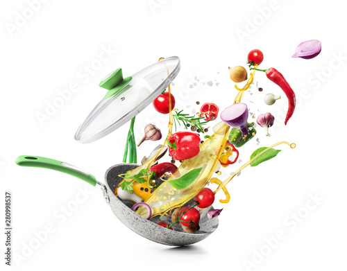 Cooking concept. Vegetables are flying out of the pan isolated on white background. Healthy food.