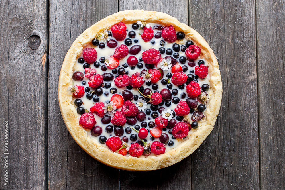 tart with different berries on a old wooden background
