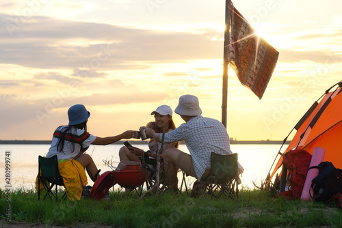 A group of Asian men and women are camping near a reservoir to relax and party, Summer Hiking concept .