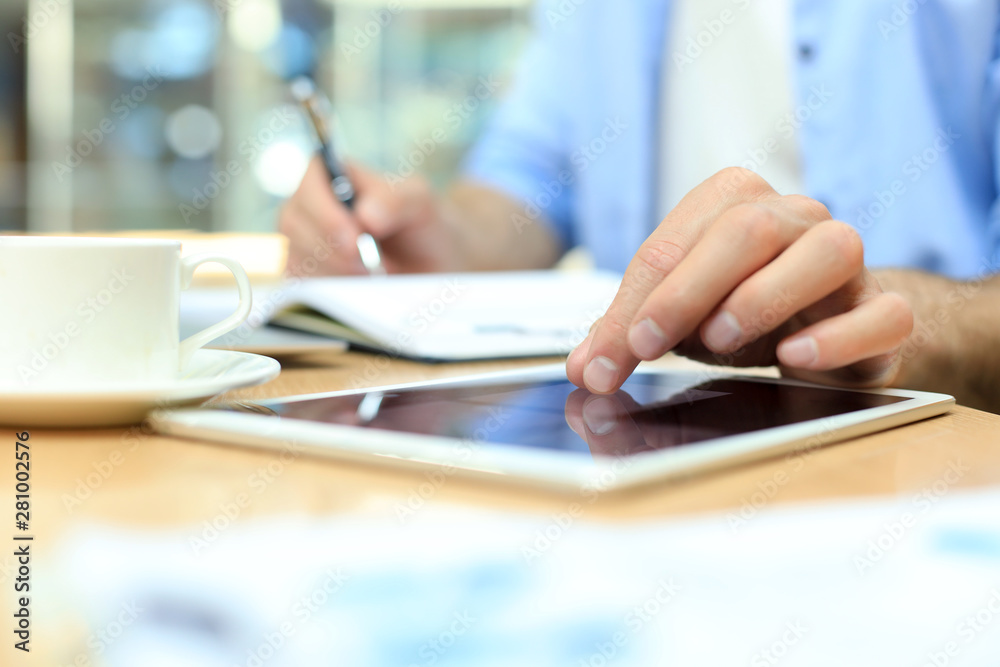 Man writing work plan with pen on paper notebook, browsing internet on digital tablet on office desk. Man writing work plan with pen on paper notebook, browsing internet on digital tablet on office desk.