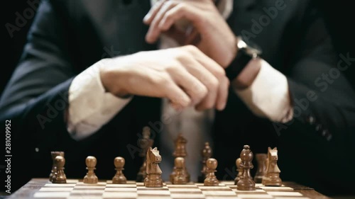 partial view of businessman sitting at table and playing chess