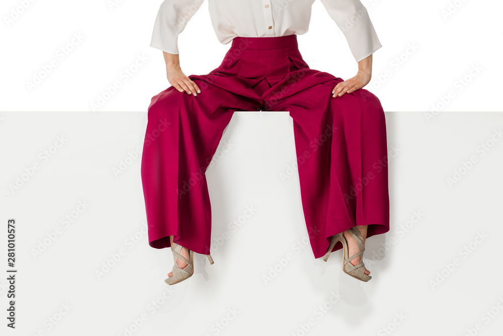 beautiful legs woman wearing burgundy trousers and high heels shoes sitting on white bench. beautiful legs woman wearing burgundy trousers and high heels shoes sitting on white bench.