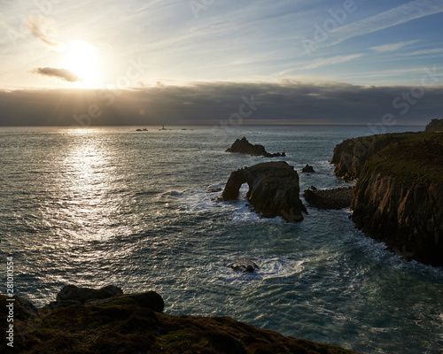 Sunset at Land's End over Enys Dodman rock arch, Longships Lighthouse, Cornwall photo