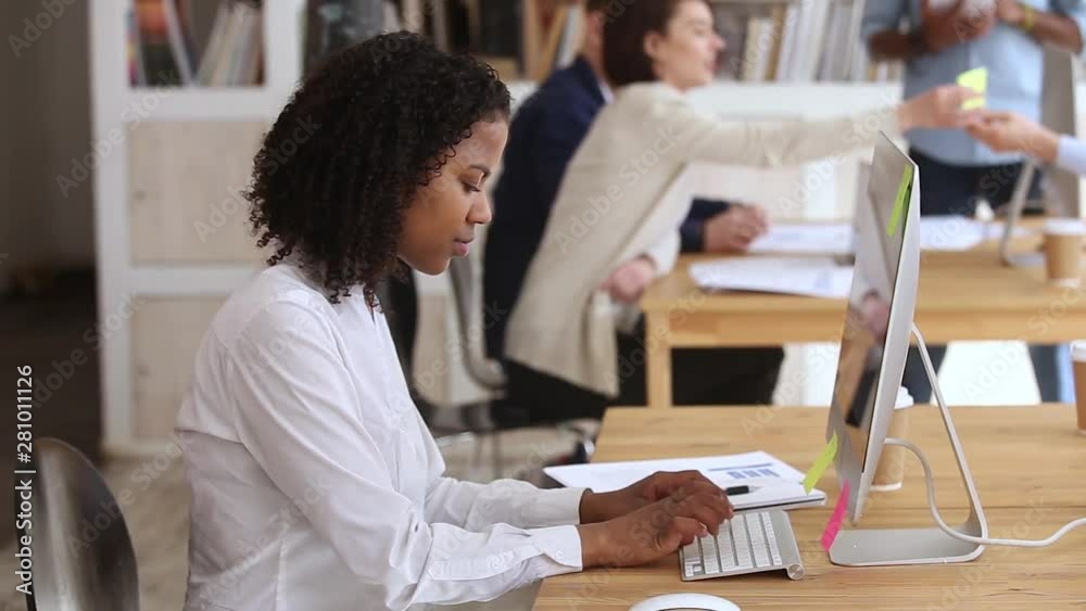 Black woman employee typing on keyboard looking at pc screen Black woman employee typing on keyboard looking at pc screen