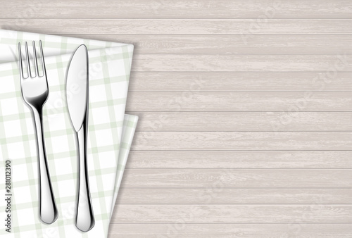 Fork and table knife on a napkin. Wooden table.