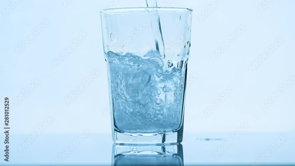 Poring carbonated soda water in drinking glass, slow motion