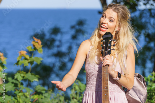 Woman playing acoustic guitar in park