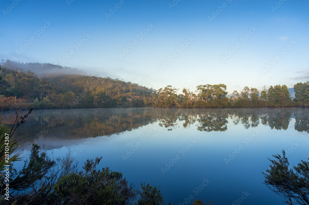 Beautiful landscape with mirror like water surface reflecting trees and sky
