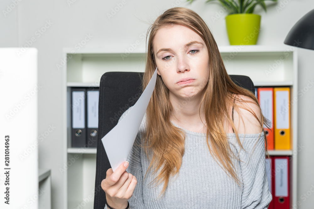 woman in the office is waving her head with a sheet of paper