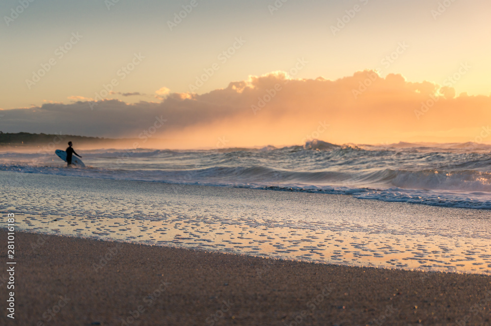 Beach sunrise seascape with surfer at the distance. Seaside summer background