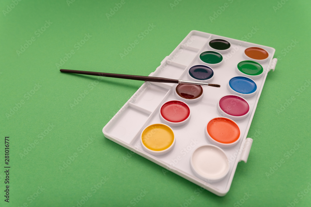 Naklejka premium Top view of watercolor paint in box on green background