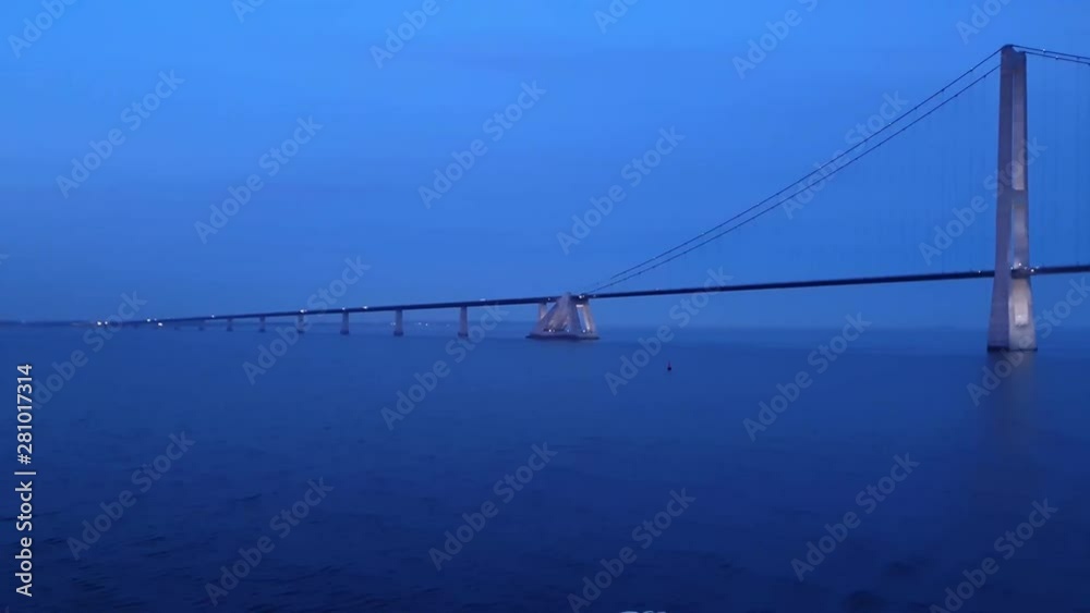 modern bridge with long ropes on large concrete supports and driving cars over blue river in early summer evening modern bridge with long ropes on large concrete supports and driving cars over blue river in early summer evening