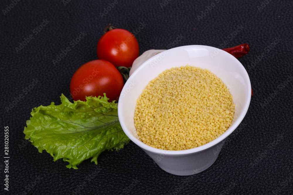 Raw couscous in the bowl served salad leaves, tomato and pepper Raw couscous in the bowl served salad leaves, tomato and pepper