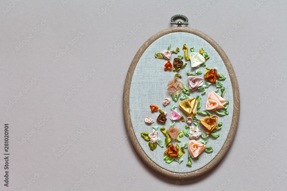 Close up view for the hand embroidery with satin, silk and nylon ribbons of flower ornament with delicate roses on hoop (the embroidery made the author of photo)